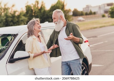 Photo of funny beautiful retired couple wear casual clothes driving car talking smiling outside urban city street