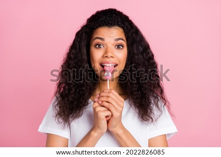 Photo of funny charming dark skin woman dressed white outfit licking lollipop isolated pink color background