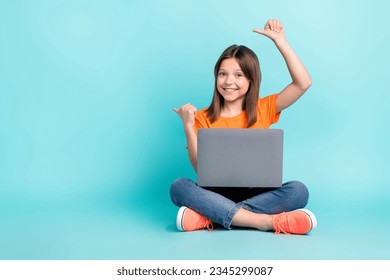 Photo of funny charming preteen age girl sitting floor advertsise modern technology empty space isolated on cyan color background - Powered by Shutterstock