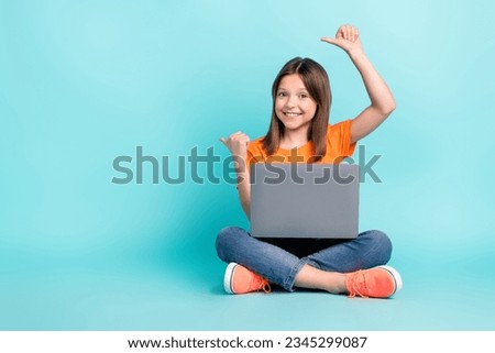 Photo of funny charming preteen age girl sitting floor advertsise modern technology empty space isolated on cyan color background