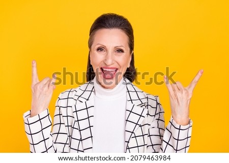 Photo of funny childish aged lady fingers make heavy metal symbol isolated on yellow color background
