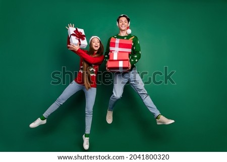 Photo of funny crazy couple hold pile giftbox enjoy jump flight wear hat ugly pullover isolated green color background