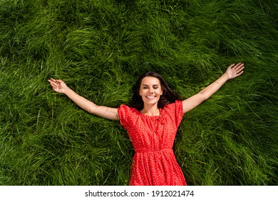 Photo of funny cute young woman dressed red off-shoulders dress relaxing green grass arms sides outdoors backyard