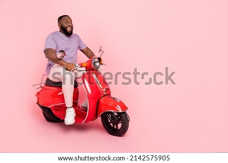Photo of funny excited guy dressed violet t-shirt driving moped empty space isolated pink color background