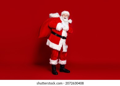 Photo of funny excited man pensioner dressed santa claus costume carrying big christmas sack smiling isolated red color background - Powered by Shutterstock