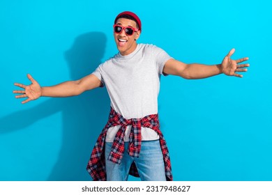 Photo of funny excited man wear grey t-shirt dark glasses open arms ready hug you isolated blue color background