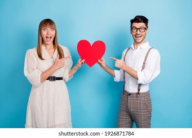 Photo Of Funny Excited Two Persons Dressed White Clothes Holding Pointing Fingers Big Paper Heart Isolated Blue Color Background