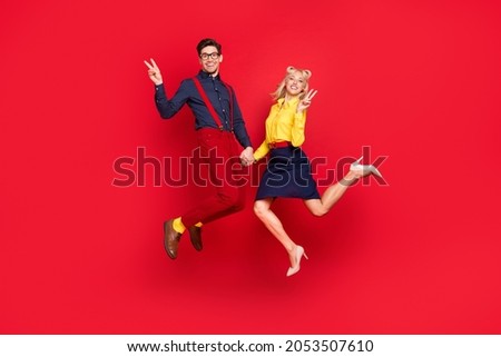 Photo of funny funky positive young lady guy dressed pinup outfits jumping high showing v-signsn isolated red color background
