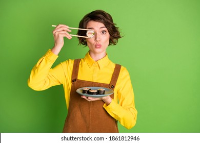 Photo Of Funny Girl Hold Chopsticks Plate Sushi Hide Eye With Roll Pout Lips Wear Yellow Shirt Overall Isolated Green Color Background