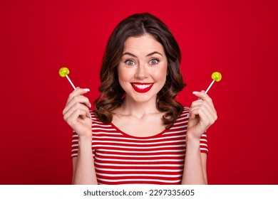Photo of funny glamorous lady hold two yellow lollipop candy addicted sugary wear striped top isolated red color background