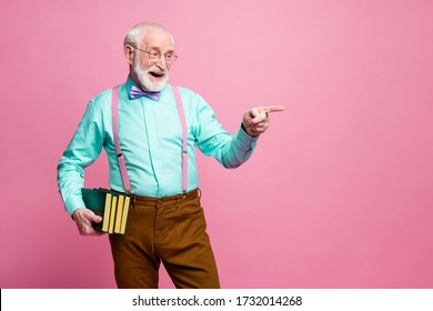 Photo of funny grandpa professor books university college direct finger empty space choose student for answer wear specs shirt suspenders bow tie pants isolated pink pastel color background