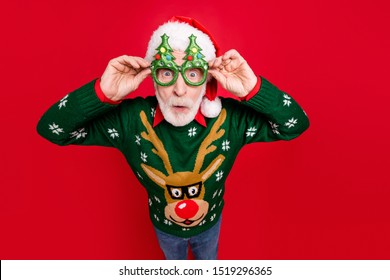 Photo Of Funny Grey Haired Santa Looking On Unbelievable Low X-mas Shopping Prices Speechless Wear X-mas Tree Shape Specs Ugly Ornament Sweater Isolated Red Background