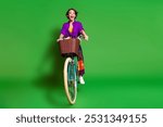 Photo of funny happy screaming young woman wear purple shirt and brown bob haircut riding bicycle isolated on green color background