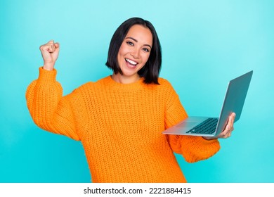 Photo of funny lucky girl dressed orange pullover winning game modern gadget rising fist isolated teal color background - Shutterstock ID 2221884415