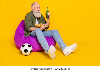 Photo Of Funny Old Man Hold Beer Bottle Chips Bowl Watch Foot Ball Wear Green Shirt Isolated Yellow Color Background