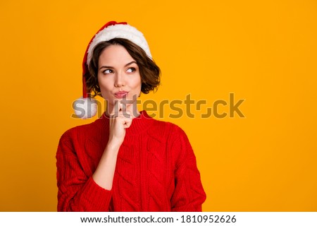 Photo of funny pretty lady celebrate winter holidays dreamy look empty space think family party hand on chin x-mas concept wear santa cap red knitted sweater isolated yellow color background