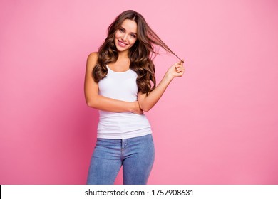 Photo of funny pretty wavy lady wind curl around finger showing perfect groomed hairstyle after treatment procedure wear white casual tank-top jeans isolated pink color background