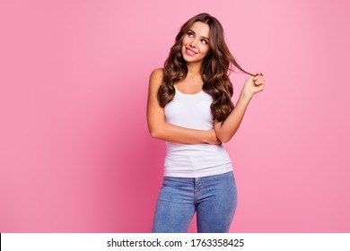 Photo of funny pretty wavy lady wind curl around finger wondered look up empty space dreamer wear white casual tank-top blue jeans isolated bright pink color background