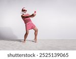 Photo of funny santa claus dressed red striped swimsuit taking selfie recording video blog isolated on white sandy beach background