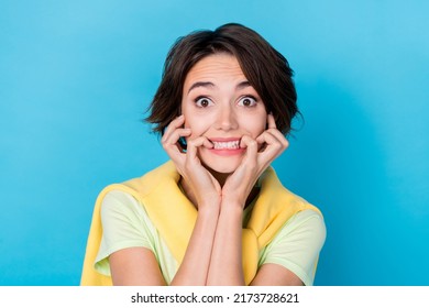 Photo of funny scared woman wear green t-shirt biting fingers big eyes isolated blue color background