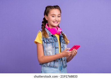 Photo Of Funny School Blond Girl Write Telephone Wear Headphones T-shirt Jeans Vest Isolated On Purple Color Background