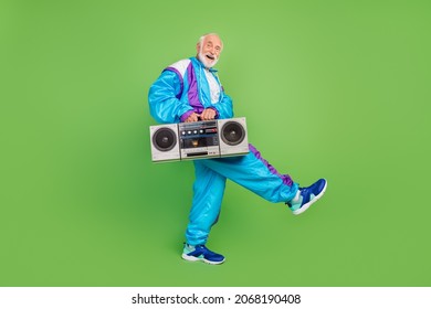 Photo of funny sweet mature guy dressed blue sport suit smiling walking listening boom box isolated green color background