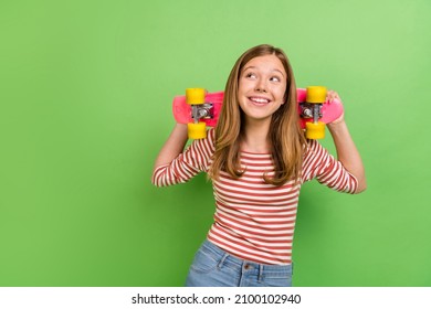 Photo of funny teen dreamy lady hold skateboard look empty space wear striped shirt isolated green color background - Powered by Shutterstock