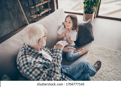 Photo of funny two people old grandpa little interested granddaughter sitting sofa telling good story stay house quarantine safety modern design interior living room indoors - Shutterstock ID 1704777145