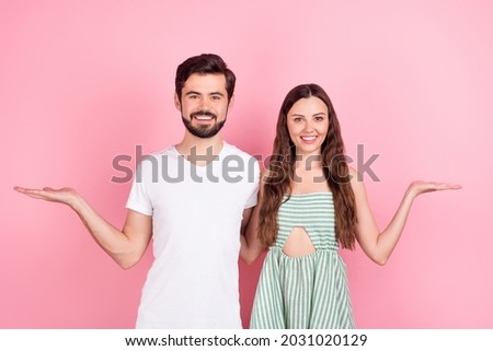 Photo of funny young brown hair couple hold empty space wear white t-shirt dress isolated on pink color backgound
