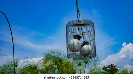 Photo of a garden lamp design in the shape of a bird cage with a clear sky background. - Shutterstock ID 2368714585