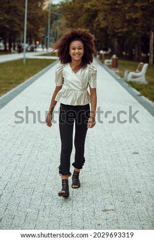 Similar – Young black woman, afro hairstyle, smiling near a wall in the street