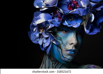 photo of the girl in blue body art image with colors from Newspapers on the head on a dark background
