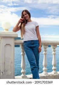 Photo of a girl leaning on the embankment parapet. The photo was taken on a clear summer day.
