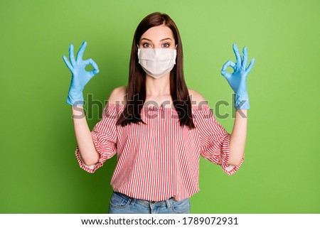 Photo of girl in medical mask show okay sign approve covid protection prevention hygiene wear rubber blue latex gloves red white clothes isolated over green color background