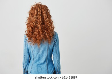 Photo Of Girl With Red Curly Hair Standing Back To Camera Over White Background. Copy Space.