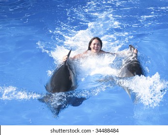 Photo of girl with two dolphin swimming underwater
