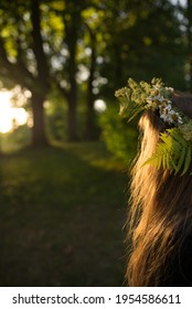 Photo of a girl wearing summer flower crown, looking away in the evening sun in the Latvian midsummer celebration Jani.