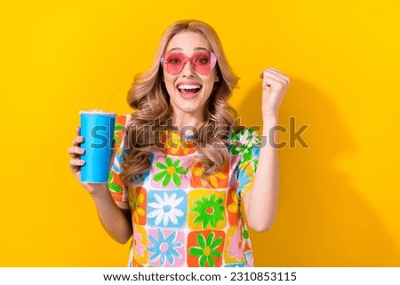 Photo glad lady drink soda cup delighted cheap cinema prices wear heart sunglass print shirt isolated yellow color background