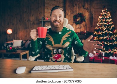 Photo of glad professional man sit desk hold coffee cup video conversation wear pullover decorated office indoors - Powered by Shutterstock