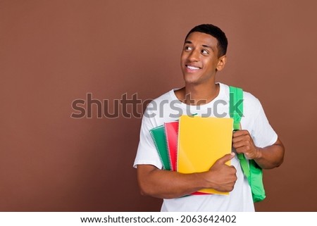 Photo of good millennial brunet guy look empty space hold copybook wear white t-shirt isolated on brown color background