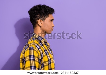 Photo of good mood attractive guy dressed checkered yellow shirt looking empty space isolated purple color background