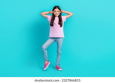 Photo of good mood charming small kid wear pink t-shirt showing two v-signs cover eyes isolated turquoise color background