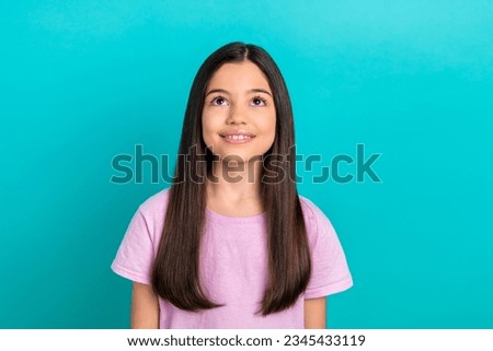 Photo of good mood dreamy small kid wear pink t-shirt looking up empty space isolated turquoise color background