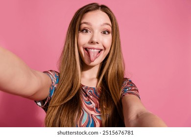 Photo of good mood eccentric girl with straight hairdo wear print t-shirt make selfie stick out tongue isolated on pink color background