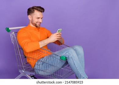 Photo Of Good Mood Man Sit In Shopping Cart Chatting With Friend About Black Friday Bargains Isolated On Violet Color Background