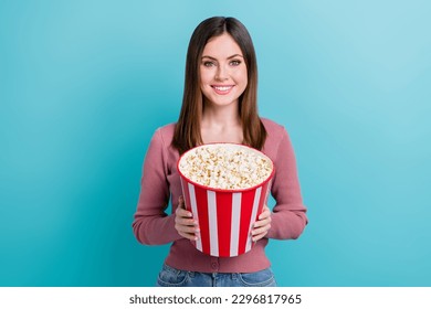 Photo of good mood optimistic girl with straight hairdo dressed pink cardigan holding popcorn in cinema isolated on blue color background