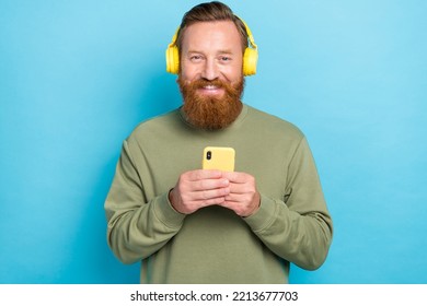 Photo Of Good Mood Satisfied Guy With Ginger Hairstyle Dressed Khaki Long Sleeve Hold Smartphone Isolated On Teal Color Background