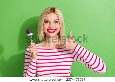 Photo of good mood woman with bob hairstyle wear striped shirt hold spoon show thumb up approve meal isolated on green color background