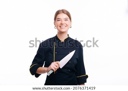 Photo of good-looking female chef stands iand holding a knive smiling at the camera.