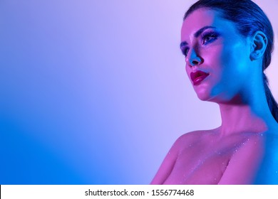 Photo of Gorgeous brunette model in the studio with color filters. Fashion, beauty, glow. Closeup face of a beautiful brunete woman in neon light purple and blue